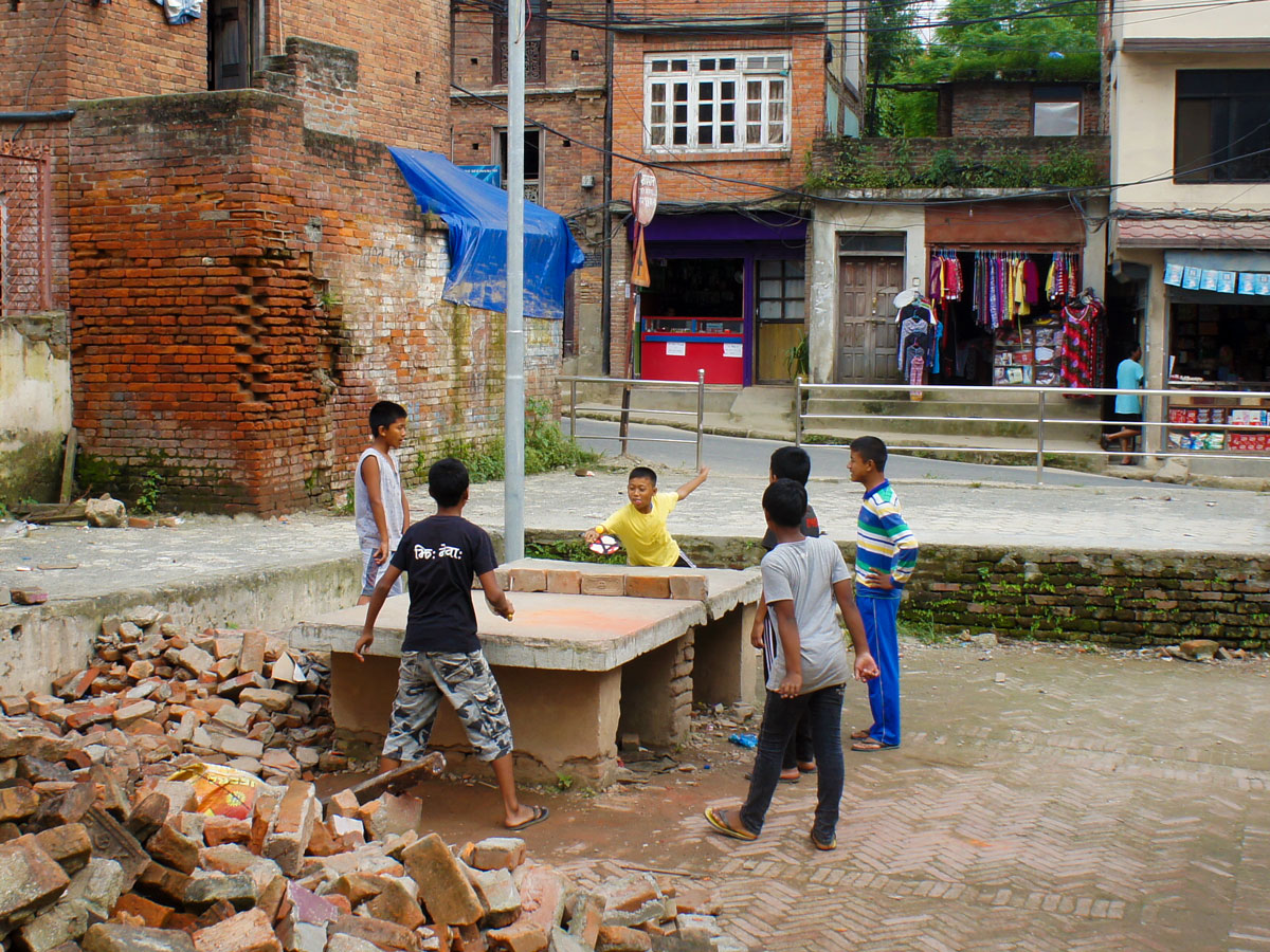 un gruppo di bambini gioca in strada su un tavolo da ping pong improvvisato