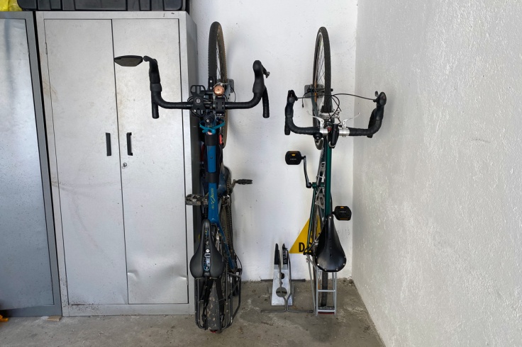 due biciclette sistemate in verticale grazie ad un supporto per la ruota anteriore vicino ad un armadietto in metallo