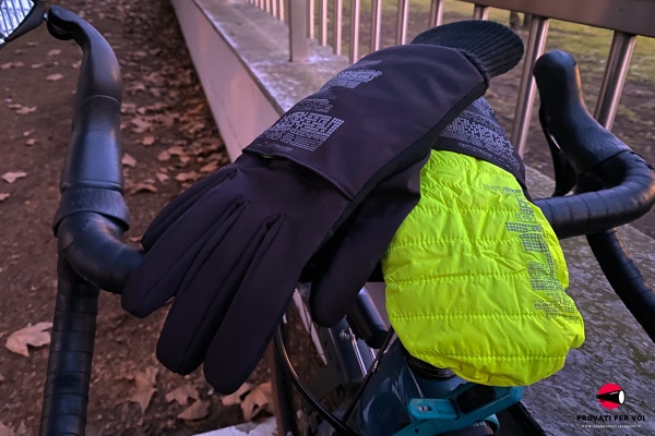 un paio di guanti invernali di colore nero con moffola color giallo fluo poggiati sul manubrio di una bicicletta