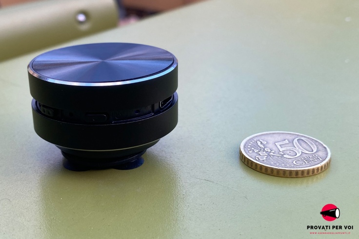 un diffusore audio di colore nero e una moneta da 50 centesimi di euro a confronto sul piano orizzontale
