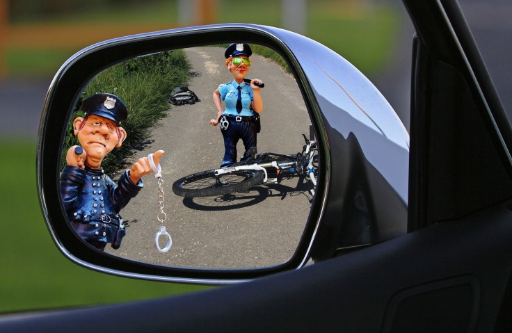 due poliziotti procedono al fermo di un automobilista dopo lo schianto con un ciclista in sella alla sua bicicletta